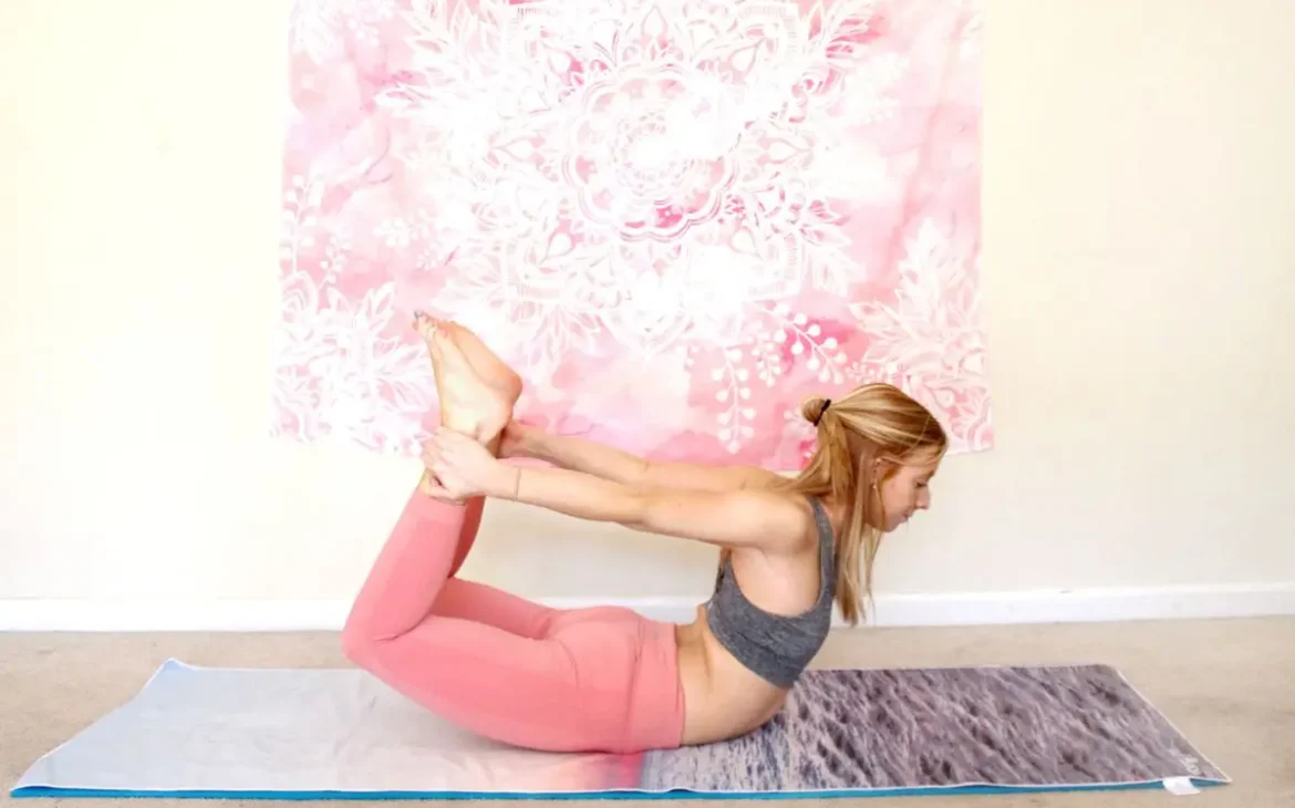 Redhead woman doing the heart opening yoga pose, bow pose, on a yoga mat indoors