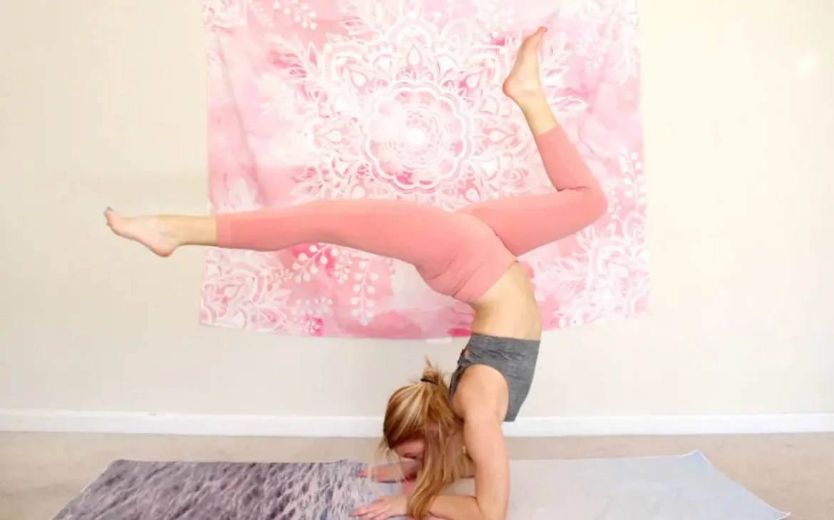 Young redhead woman doing the heart opening yoga pose, wheel pose with elbows down, on a yoga mat indoors