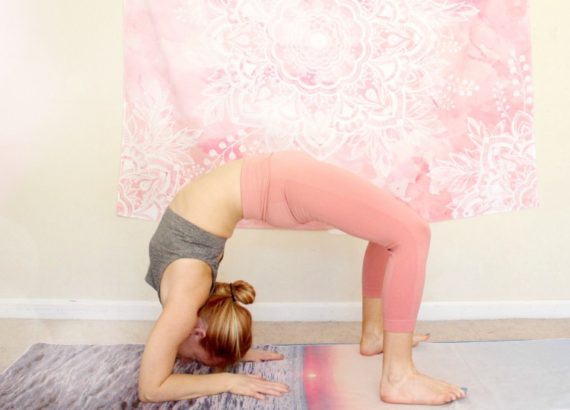 Young redhead woman doing the heart opening yoga pose, warrior one, on a yoga mat indoors