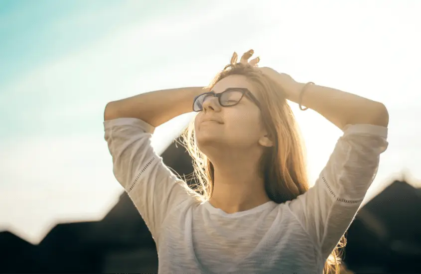 Woman facing up toward the sun, showing that she is happy and at peace