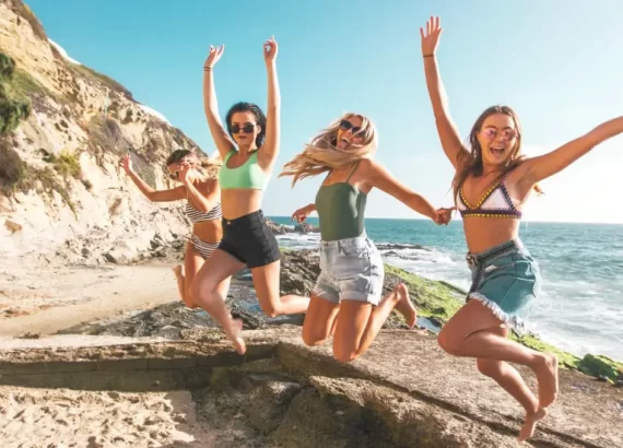 Happy group of girls who are jumping on the beach, to demonstrate the power of affirmations for more happiness