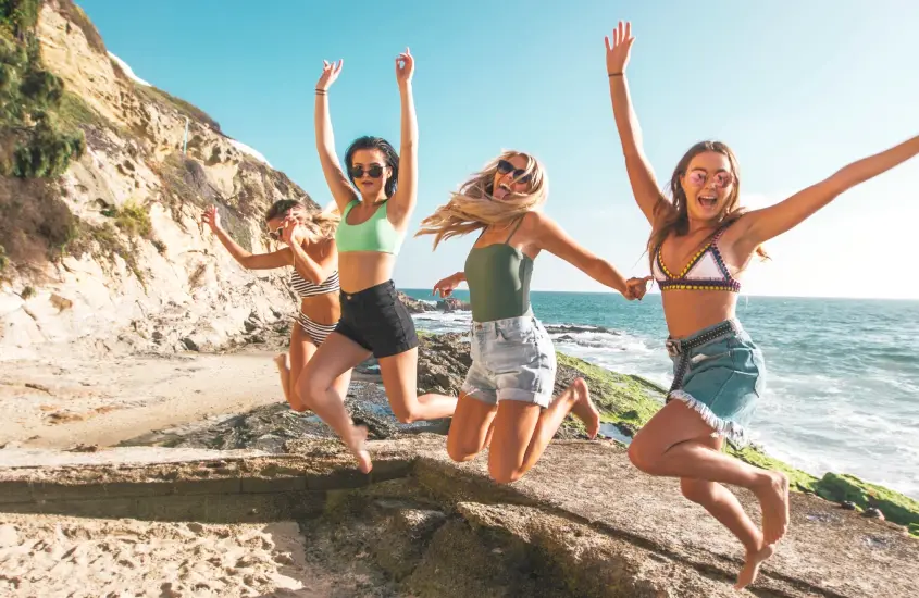 Happy group of girls who are jumping on the beach, to demonstrate the power of affirmations for more happiness