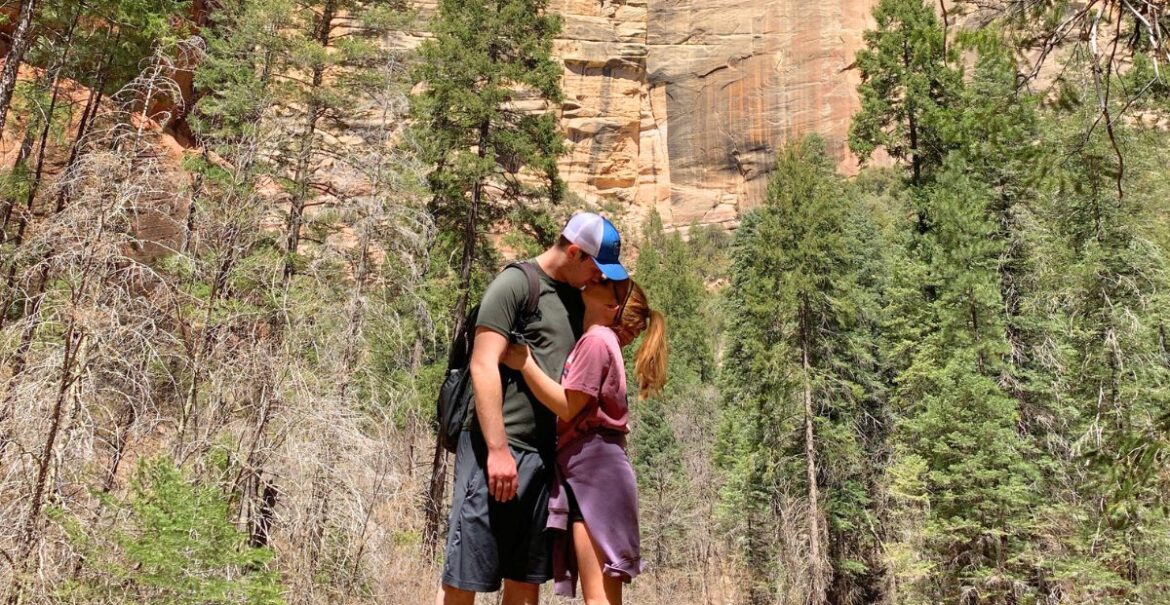 Cover image for the how to be a better partner blog, showing a couple kissing in a beautiful scenic woods