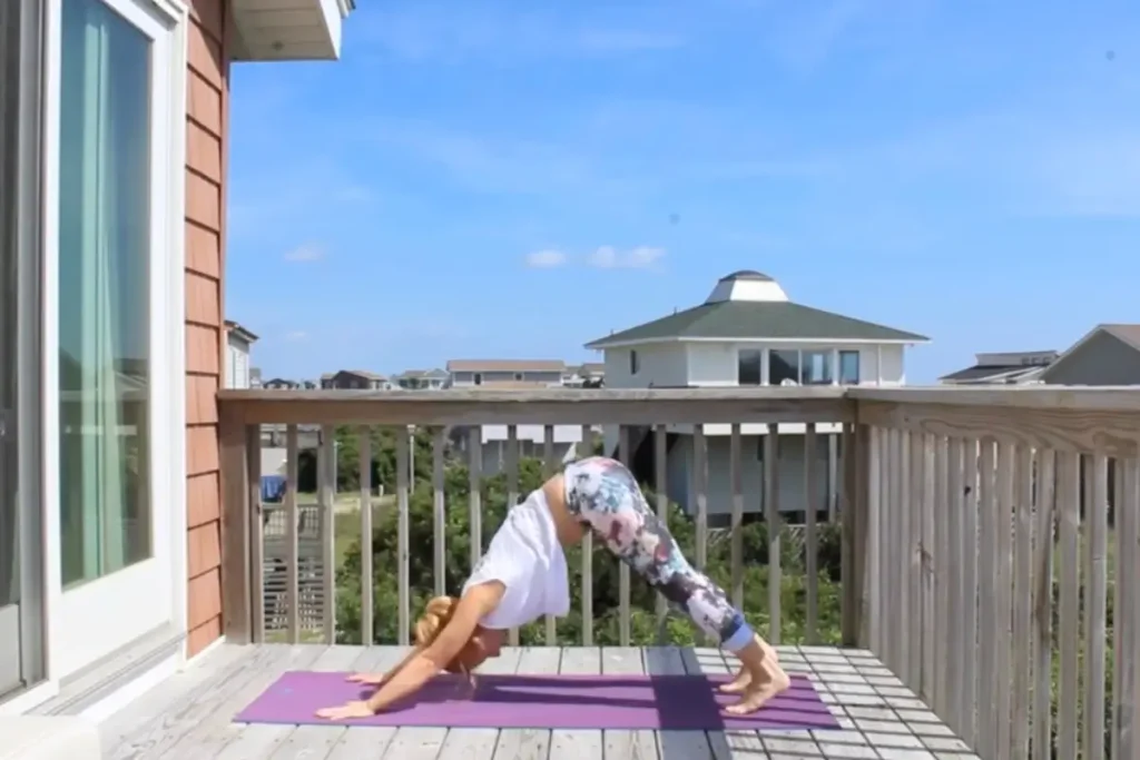 Redhead woman doing the down dog yoga pose on a sunny deck