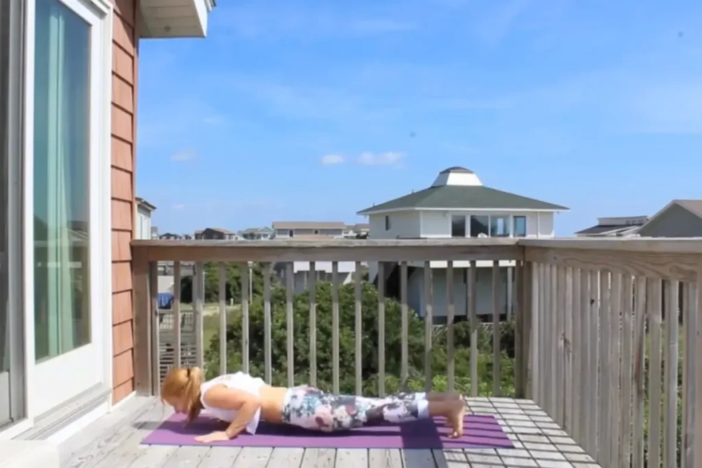 Redhead woman in a low push up position on a sunny deck