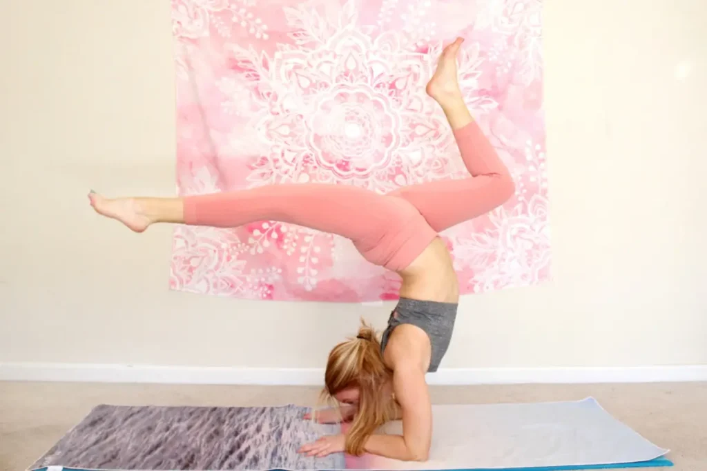 Young redhead woman doing the heart opening yoga pose, wheel pose with elbows down, on a yoga mat indoors