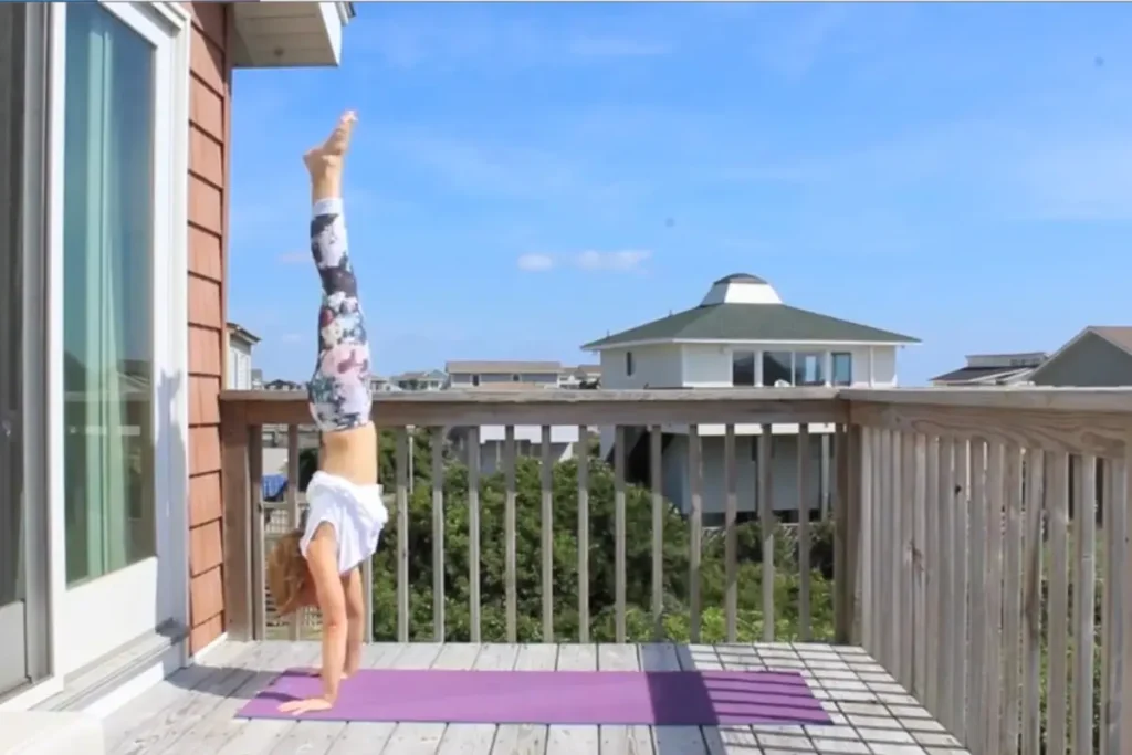 Redhead woman doing a handstand on a sunny deck