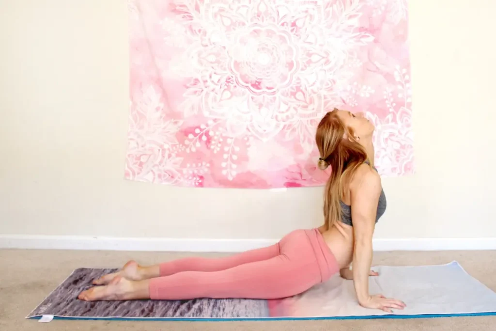 Redhead woman doing upward dog heart opening yoga pose on a yoga mat indoors