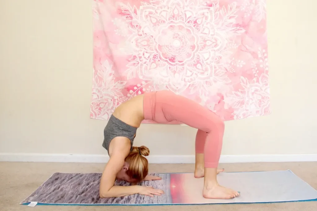 Woman doing a bridge with forearms down as part of a heart opening yoga sequence for advanced yogis
