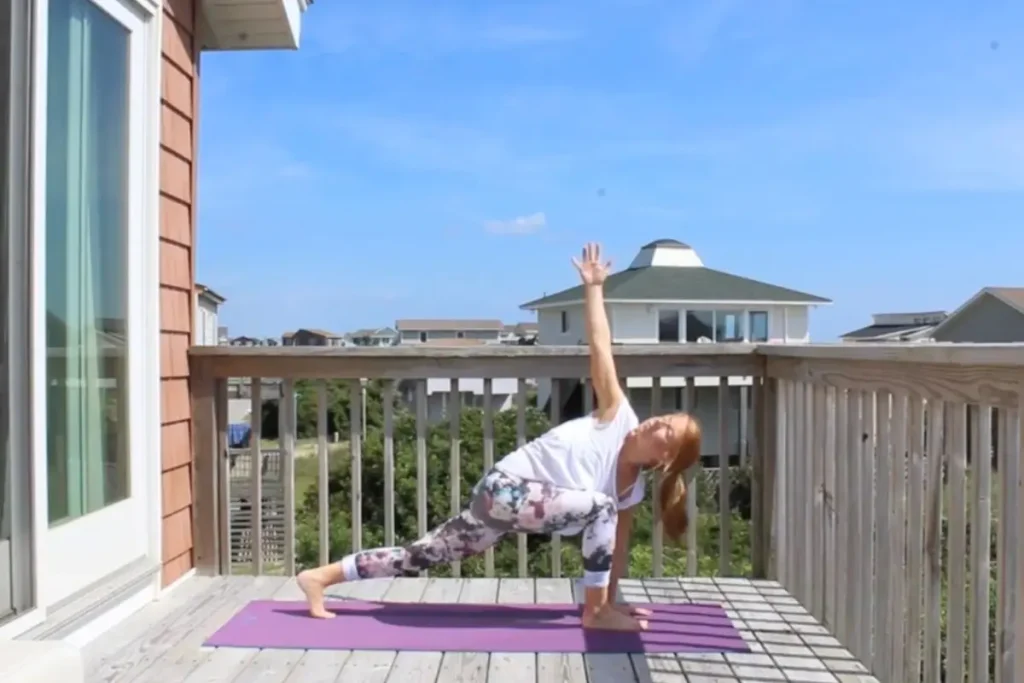 Redhead woman doing revolved side angle yoga pose on a sunny deck