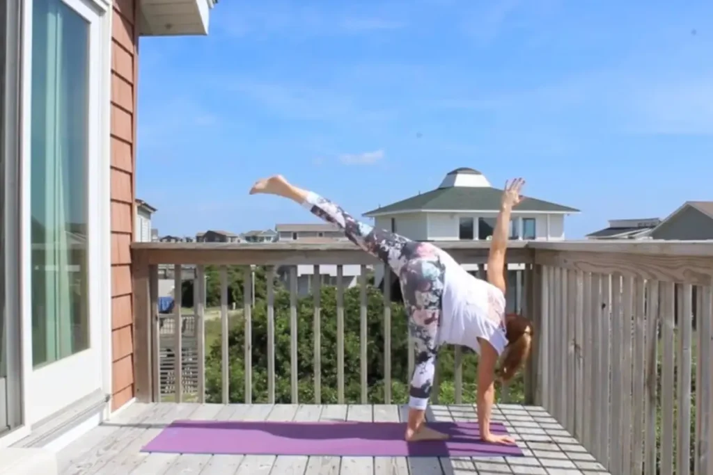 Redhead woman doing the half moon pose on a sunny deck